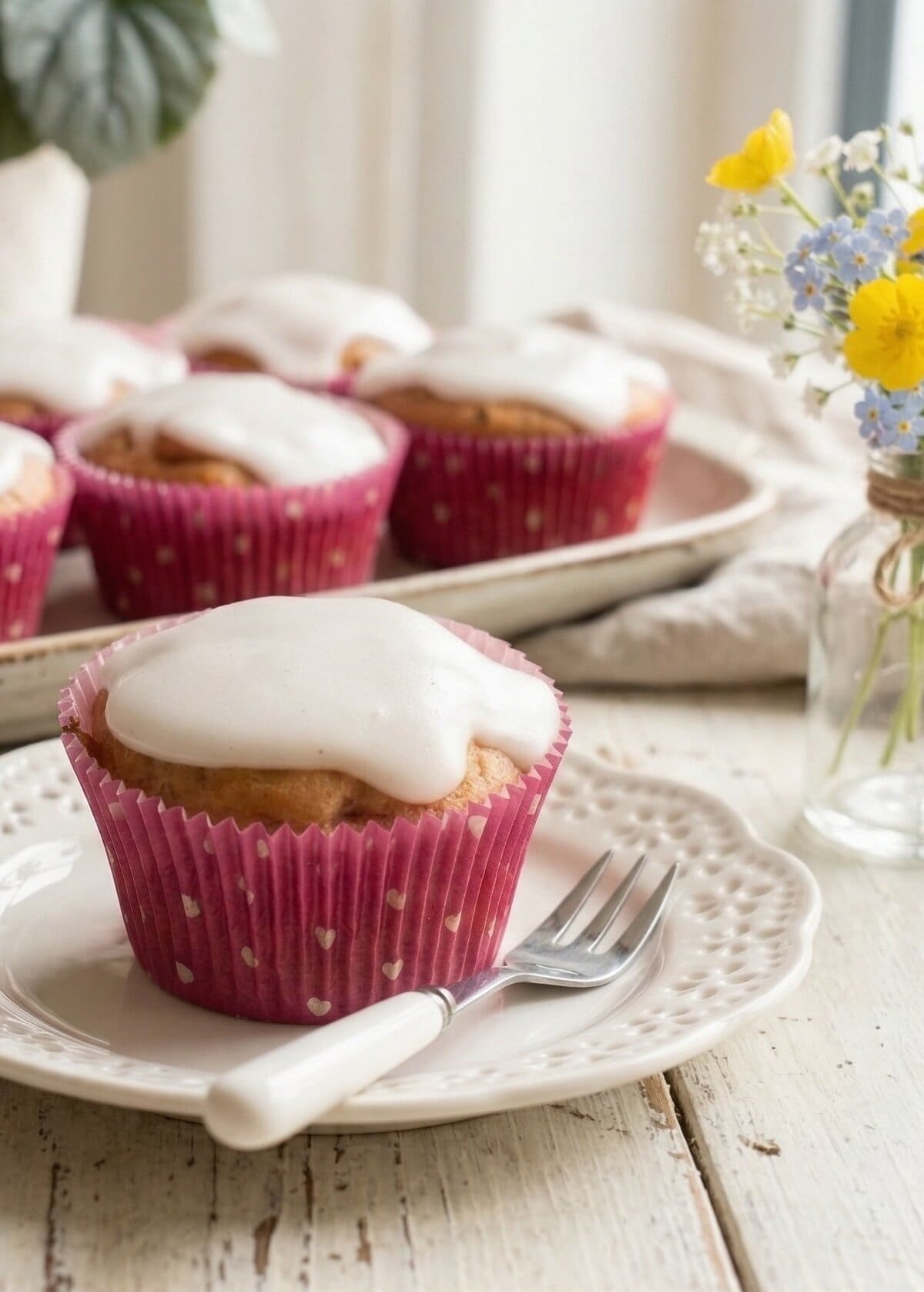 Muffins in rosa Förmchen mit Zuckerguss auf einer Platte, bzw. auf einem weißen Teller