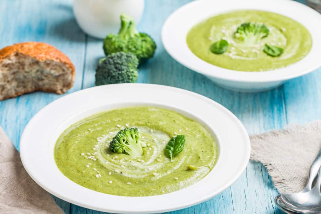 Brokkolisuppe garniert mit Brokkoliröschen auf blauem Holztisch – Foto: gettyimages/ Roxiller