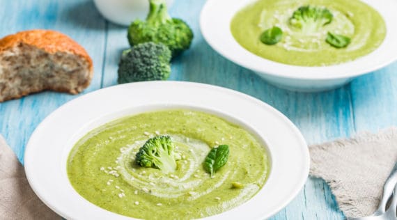 Brokkolisuppe garniert mit Brokkoliröschen auf blauem Holztisch – Foto: gettyimages/ Roxiller