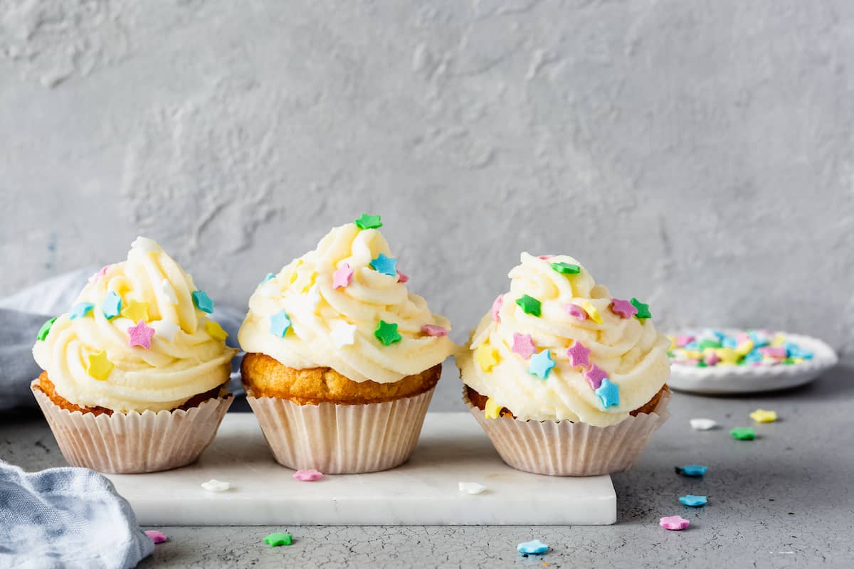 Drei Cupcakes mit Frosting und bunten Streuseln