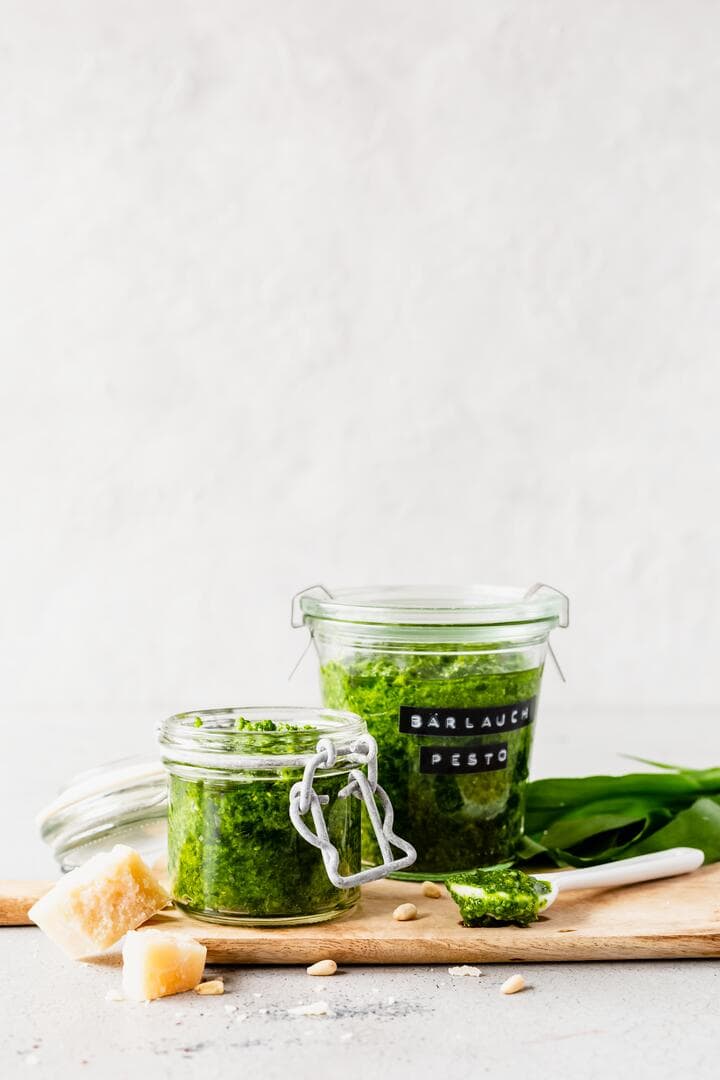 Zwei Gläser mit Bärlauchpresto auf einem Holzbrett