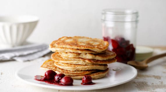 Gestapelte Pancakes auf weißem Teller mit Kirschkompott