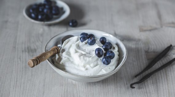 Quark mit Blaubeeren in einer hellen Schale, daneben Serviette und Besteck