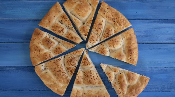 Fladenbrot in acht Teile geschnitten auf blauem Untergrund