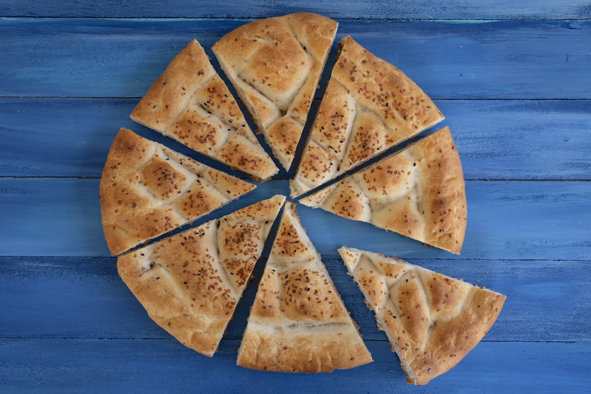 Fladenbrot in acht Teile geschnitten auf blauem Untergrund