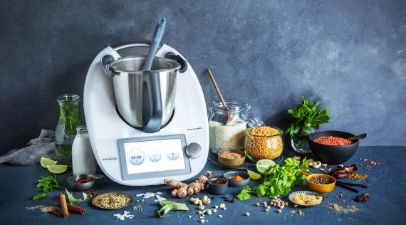 Ein Thermomix® umgeben von Lebensmitteln vor einem grauen Hintergrund – Foto: Anna Gieseler