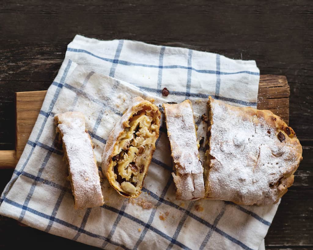 Aufgeschnittener Apfelstrudel mit Rosinen auf Geschirrtuch von oben fotografiert