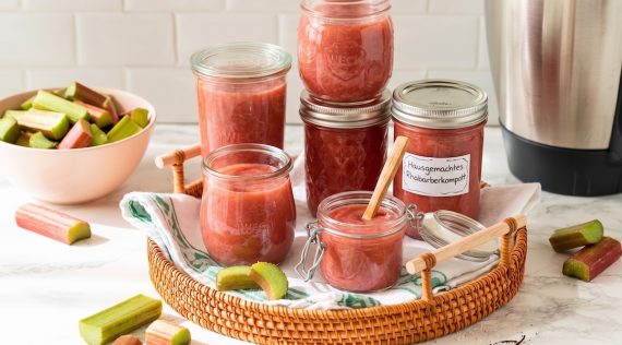 Mehrere Gläser mit Rhabarberkompott auf einem Tablett, im Hintergrund ein Thermomix® – Foto: Falkemedia KI
