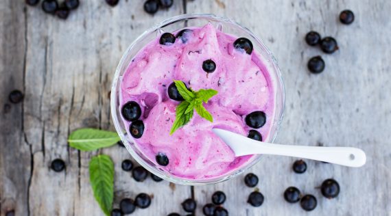 Frozen Joghurt mit Heidelbeeren aus dem Thermomix® von oben fotografiert auf grauem Holz