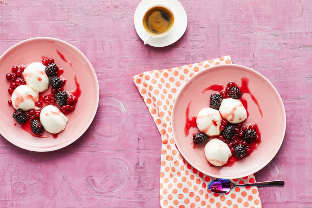 Zwei rosafarbene Schalen mit Quark-Mousse mit Beeren aus dem Thermomix® auf pinkfarbenem Untergrund