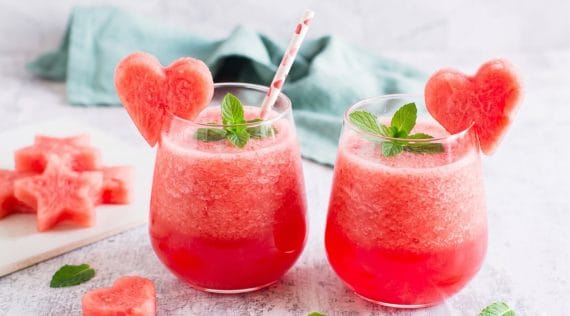 Zwei Gläser mit einem roten Getränk, garniert mit einem Stück Wassermelone