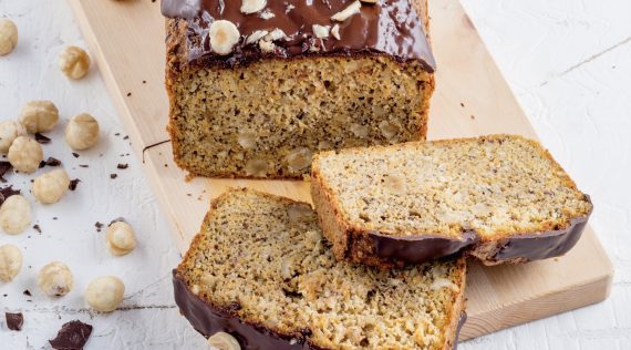 Nusskuchen angeschnitten mit Schokoglasur und Haselnüssen garniert – Foto: Stockfood