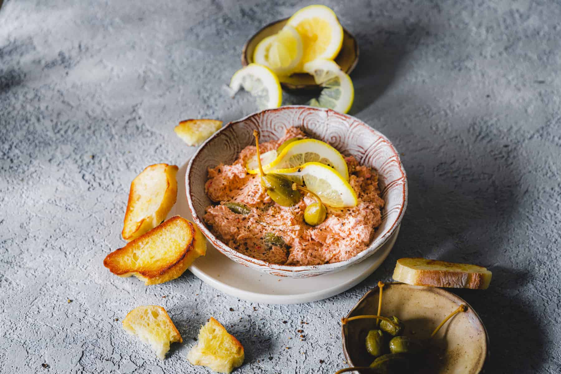 Rötlicher Thunfisch-Dip aus dem Thermomix® in einer grauen Schale, mit einer Zitrone garniert – Foto: Tina Bumann