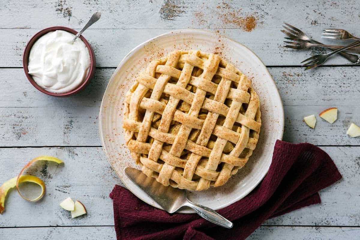 Apple Pie auf einem weißen Teller von oben fotografiert, danaben ein Schälchen mit Sahne