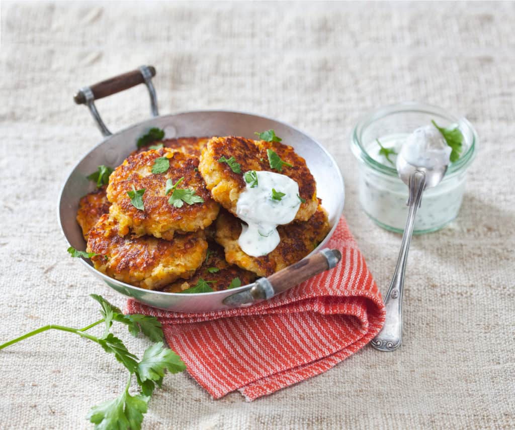 Metallpfanne mit Linsen-Zucchini-Bratlingen auf rotem Geschirrzuch