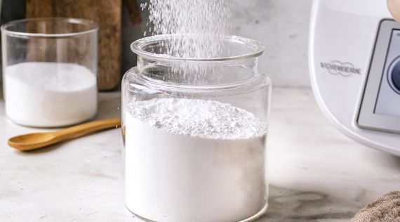 Ein Glas mit Puderzucker, in da noch mehr Zucker hineinrieselt. Daneben steht ein Thermomix® – Foto: Sandra Leibinger