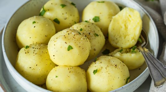 Kartoffelknödel in einer hellgrauen Schale mit etwas Petersilie bestreut