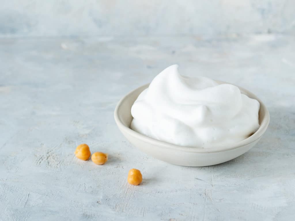 Veganer Eischnee in einer Schüssel auf grauem Untergrund