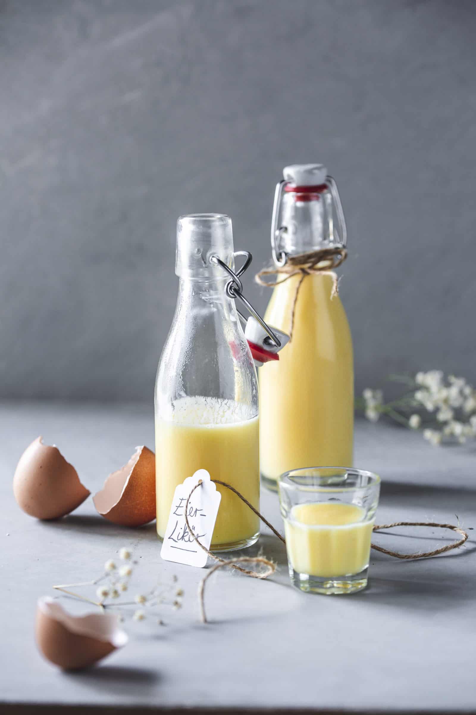 Zwei Flaschen Eierlikör, im Vordergrund ein Glas mit Likör