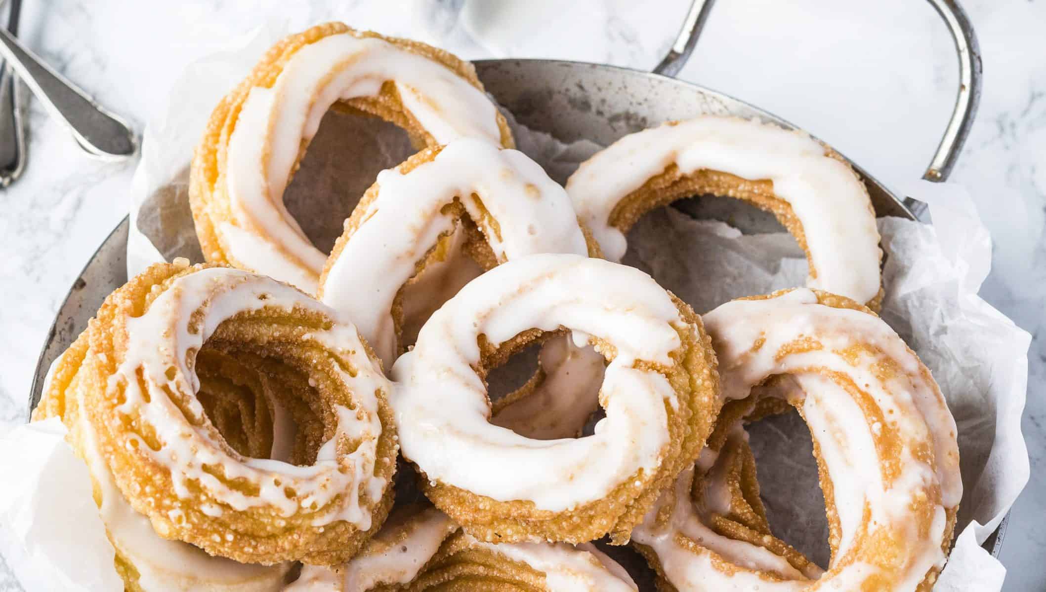 Feine Spritzkuchen mit Zuckerguss in einer Pfanne mit Butterbrotpapier