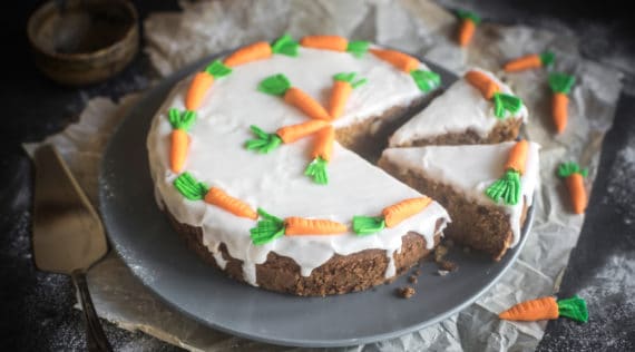 Zucchini-Karotten-Kuchen mit Zuckerguss und -Karotten dekoriert, angeschnitten