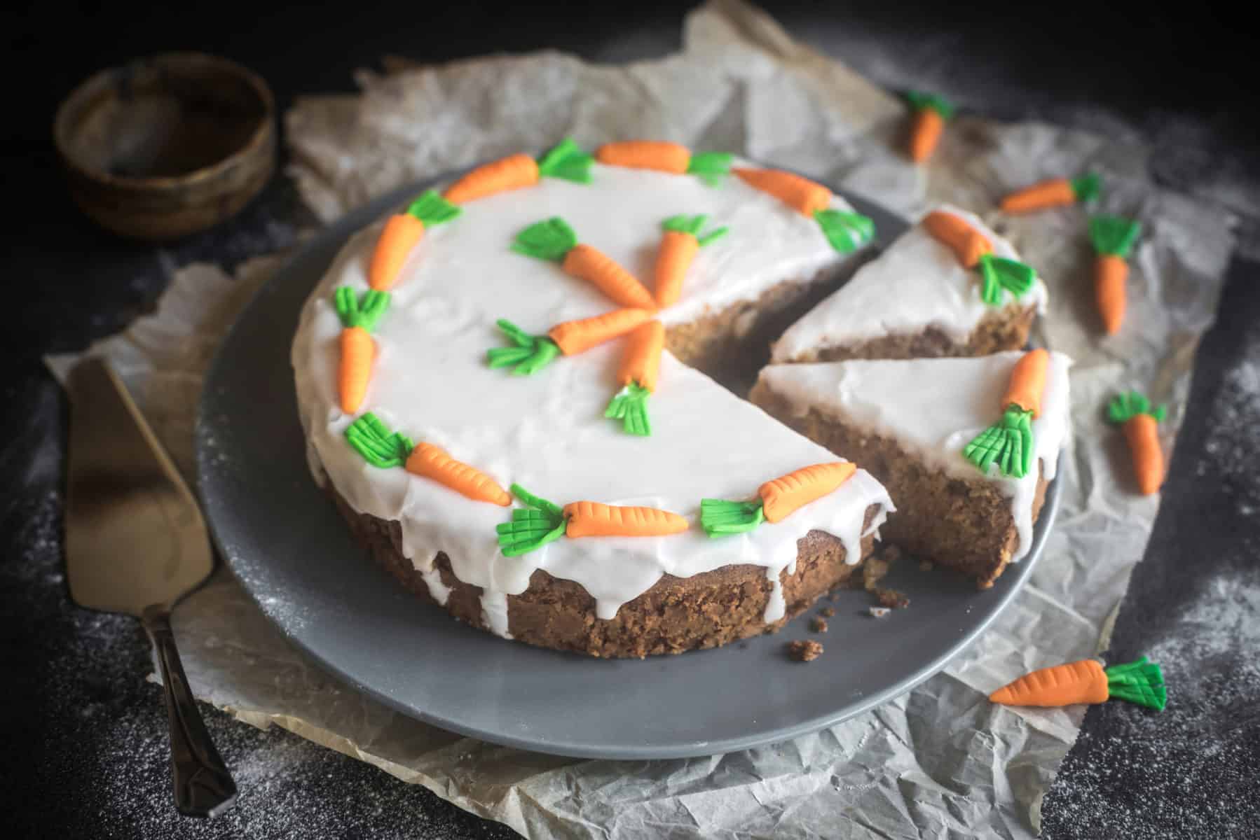 Zucchini-Karotten-Kuchen mit Zuckerguss und -Karotten dekoriert, angeschnitten