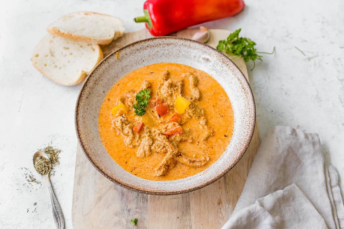Ein Teller mit orangefarbener Suppe, die helles Fleisch enthält, von oben fotografiert – Foto: Sandra Leibinger