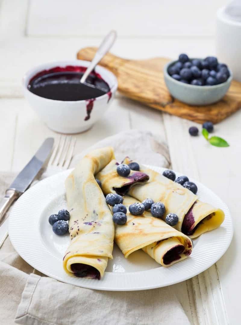 Mehrere Pfannkuchen aufgerollt auf einem Teller, mit Blaubeeren garniert – Foto: Désirée Peikert
