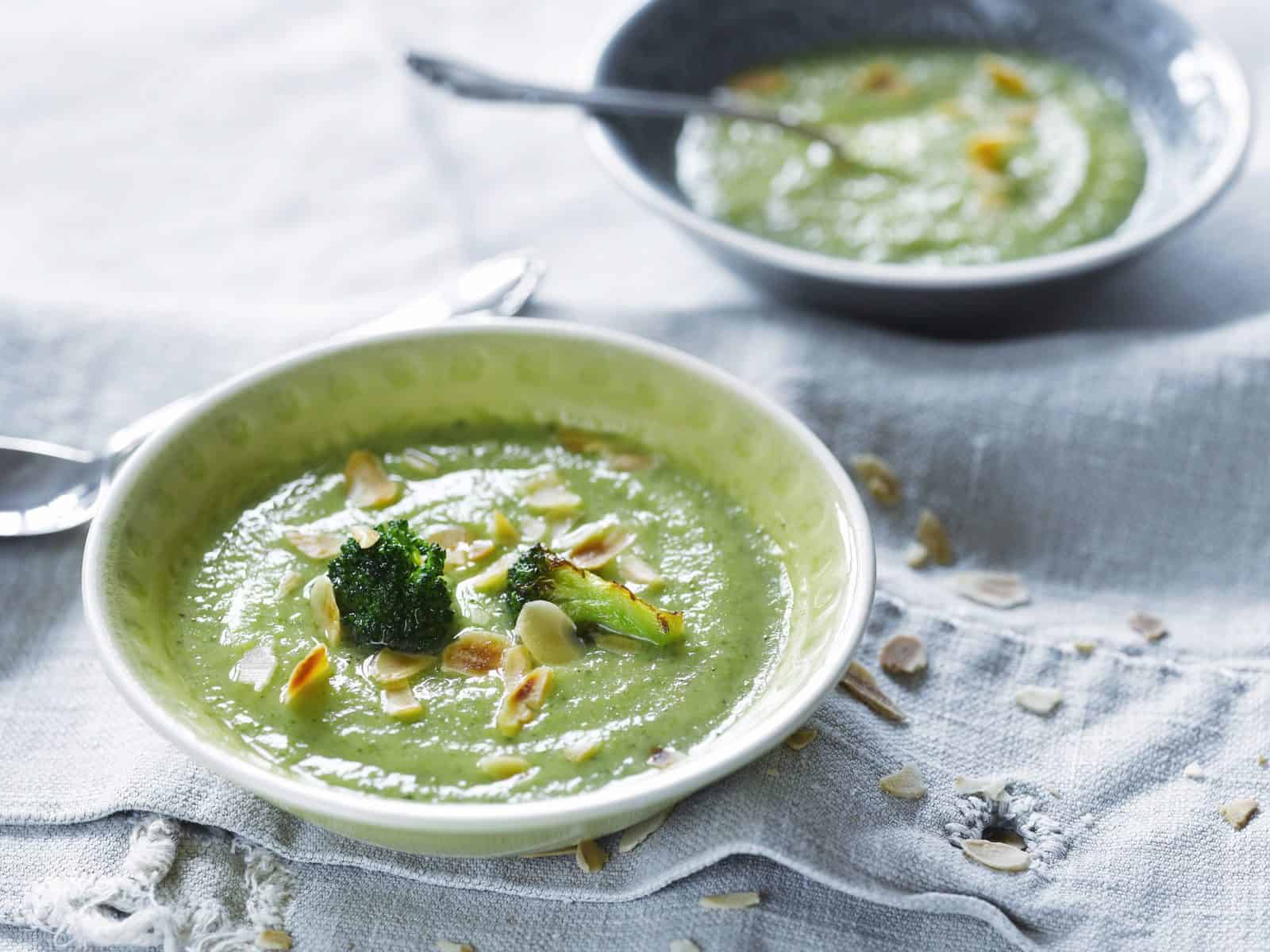 Zwei Teller mit Brokkolisuppe, garniert mit Mandelblättchen