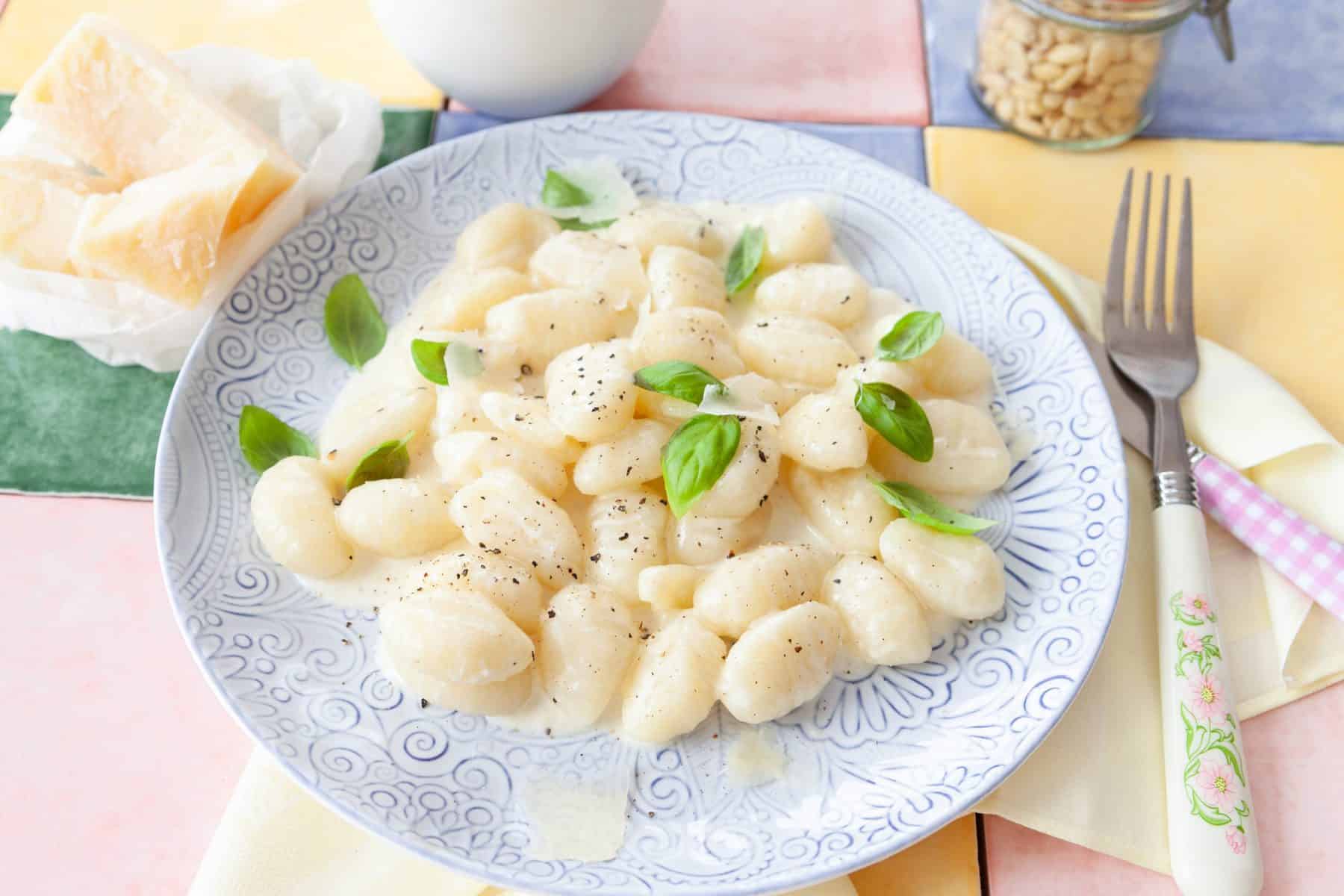 Gnocchi mit Käsesoße auf einem weißen Teller mit Basilikum garniert