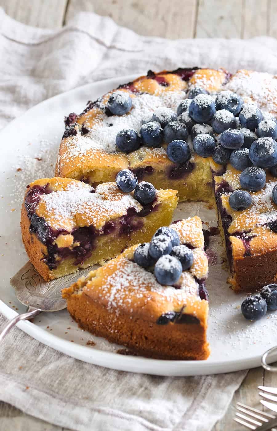 Blaubeerkuchen auf einem weißen Teller, angeschnitten