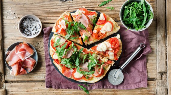 Fladenbrotpizza mit Rucola und Schinken von oben fotografiert