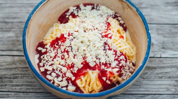 Spaghettieis mit Erdbeersoße und weißen Schokoraspeln in einer Schüssel von oben fotografiert