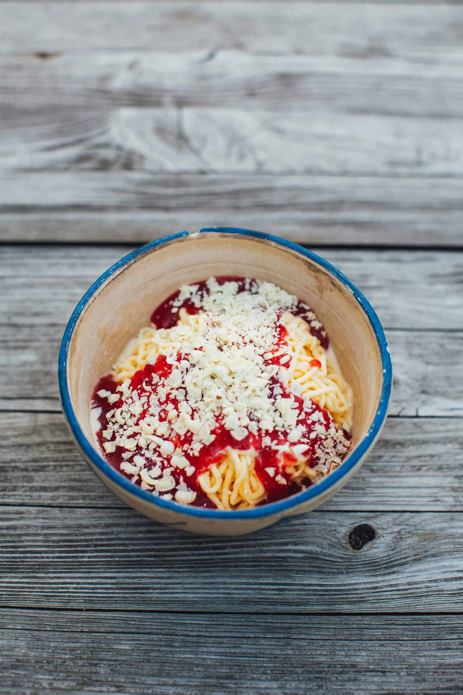 Spaghettieis mit Erdbeersoße und weißen Schokoraspeln in einer Schüssel von oben fotografiert