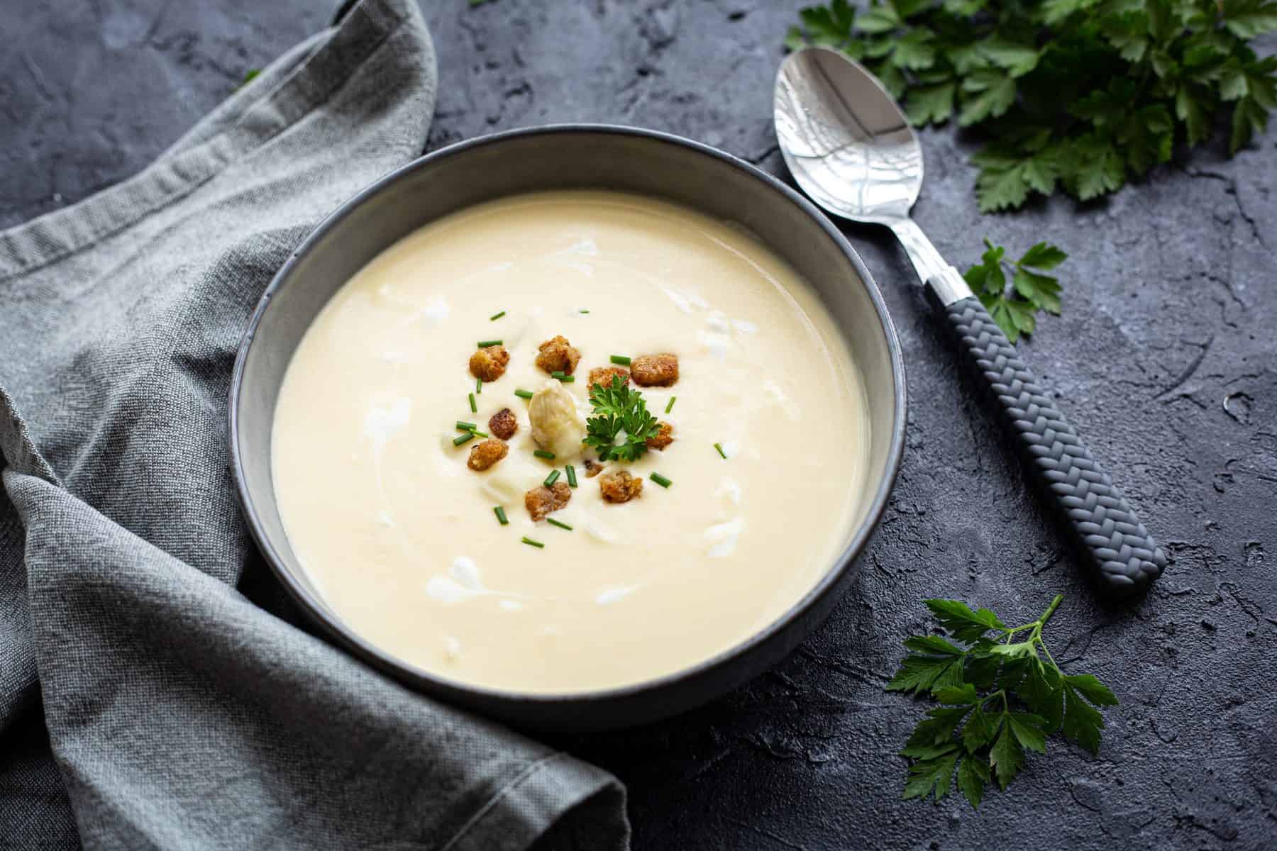 Spargelsuppe in einer grauen Schale mit Croûtons und Petersilie garniert