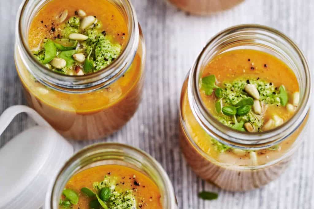 Tomatensuppe in Gläsern mit Pesto und Pinienkernen von oben fotografiert