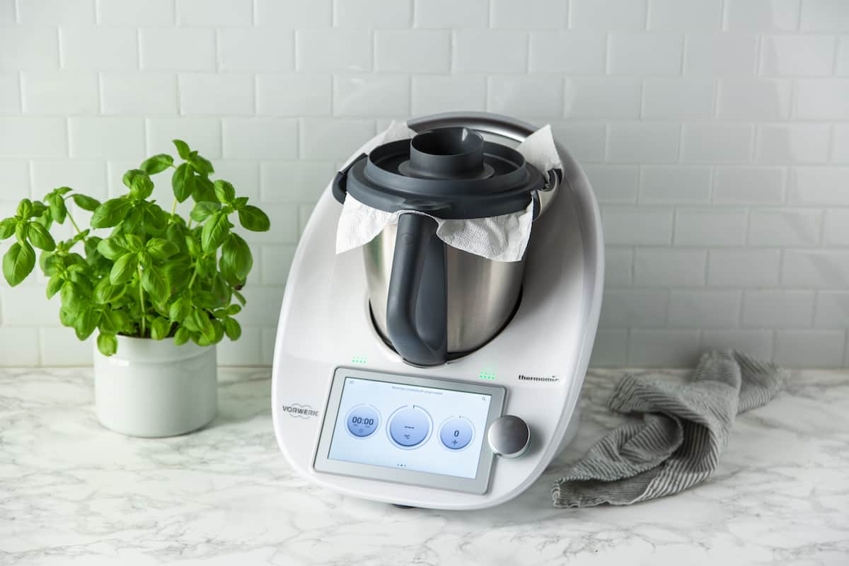 Der Thermomix® mit einem Küchentuch zwischen Mixtopf und Deckel – gegen Staubentwicklung