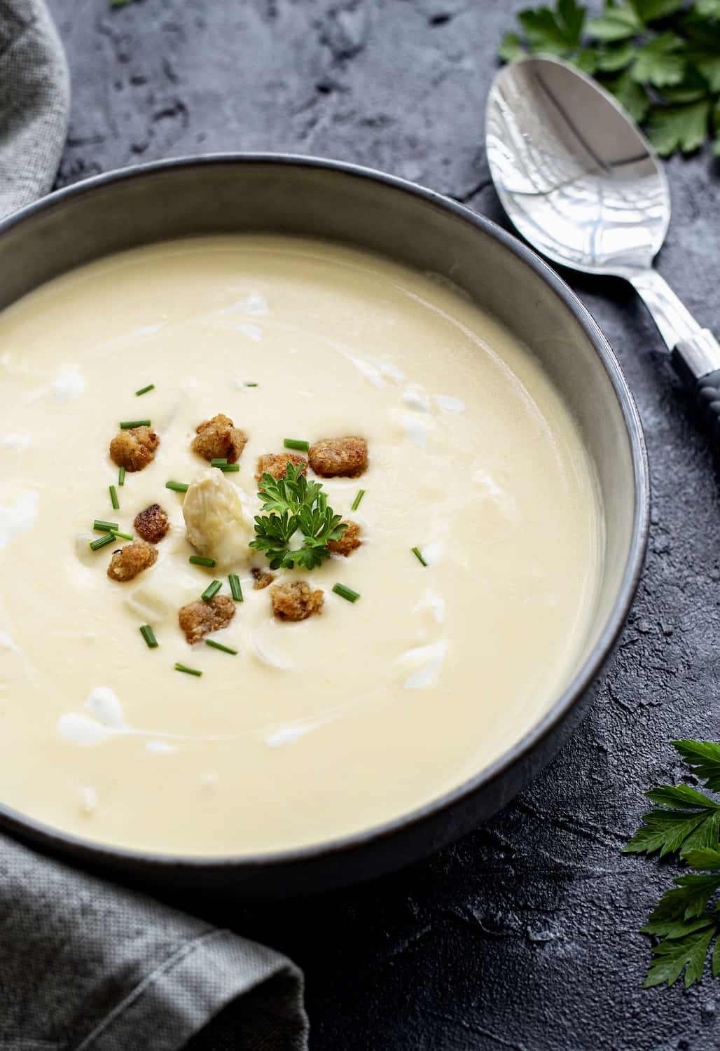 Spargelsuppe in einer grauen Schale mit Croûtons und Petersilie garniert