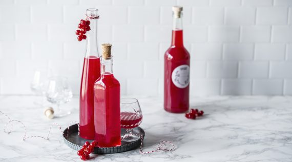 Drei flaschen mit rotem Johannisbeerlikör und ein Glas