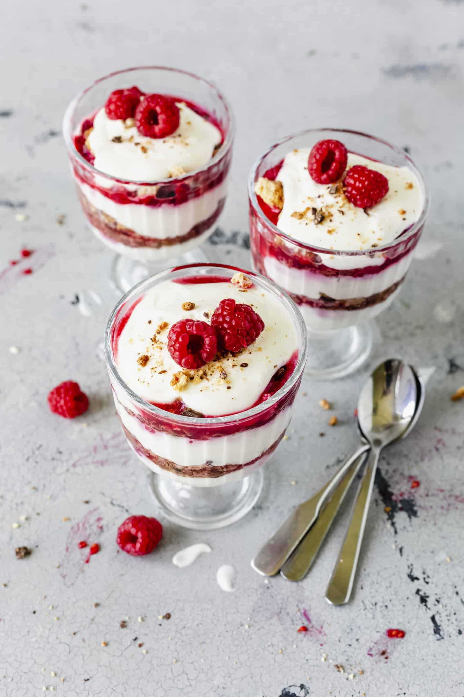 Cantuccini-Dessert in drei Gläsern mit Himbeeren garniert auf hellem Untergrund