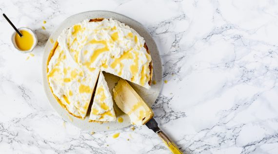 Eierlikör-Käsekuchen auf einer hellen Marmorplatte, zwei Stücken angeschnitten