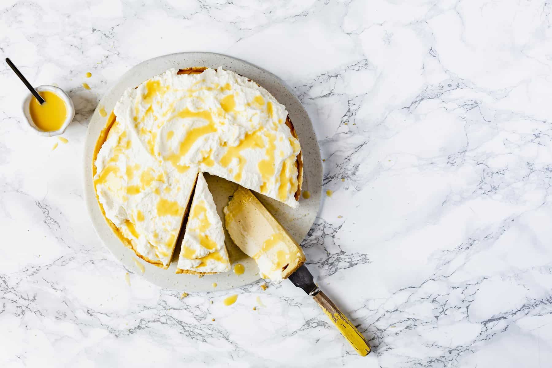 Eierlikör-Käsekuchen auf einer hellen Marmorplatte, zwei Stücken angeschnitten