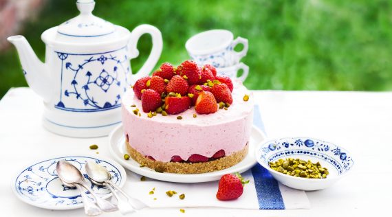 Erdbeertorte mit Joghurt-Creme und ganzen Erdbeeren auf einer Kaffeetafel im Grünen