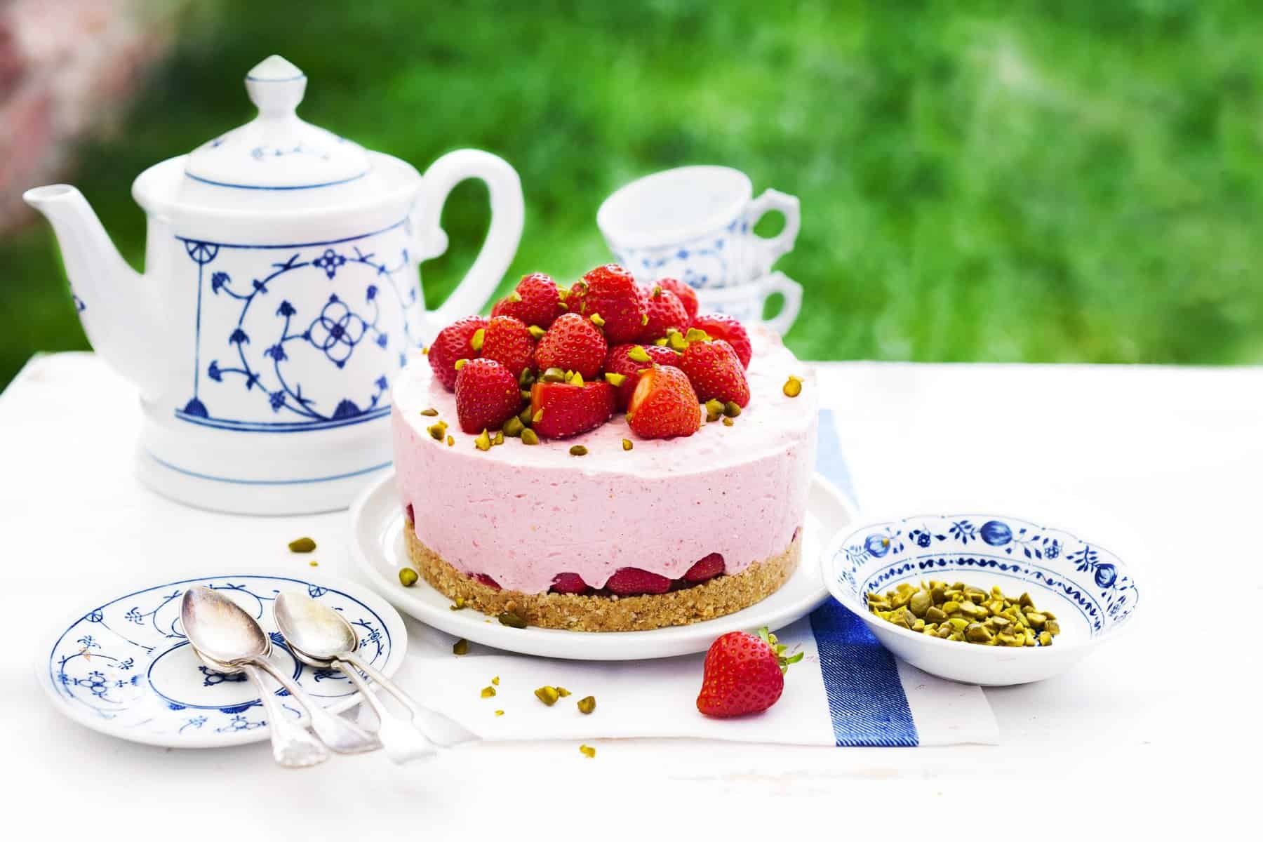 Erdbeertorte mit Joghurt-Creme und ganzen Erdbeeren auf einer Kaffeetafel im Grünen