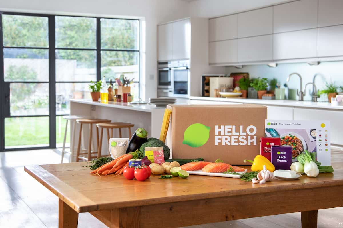 HelloFresh Kochbox auf einem Küchentisch, umgeben von Gemüse und Lebensmitteln