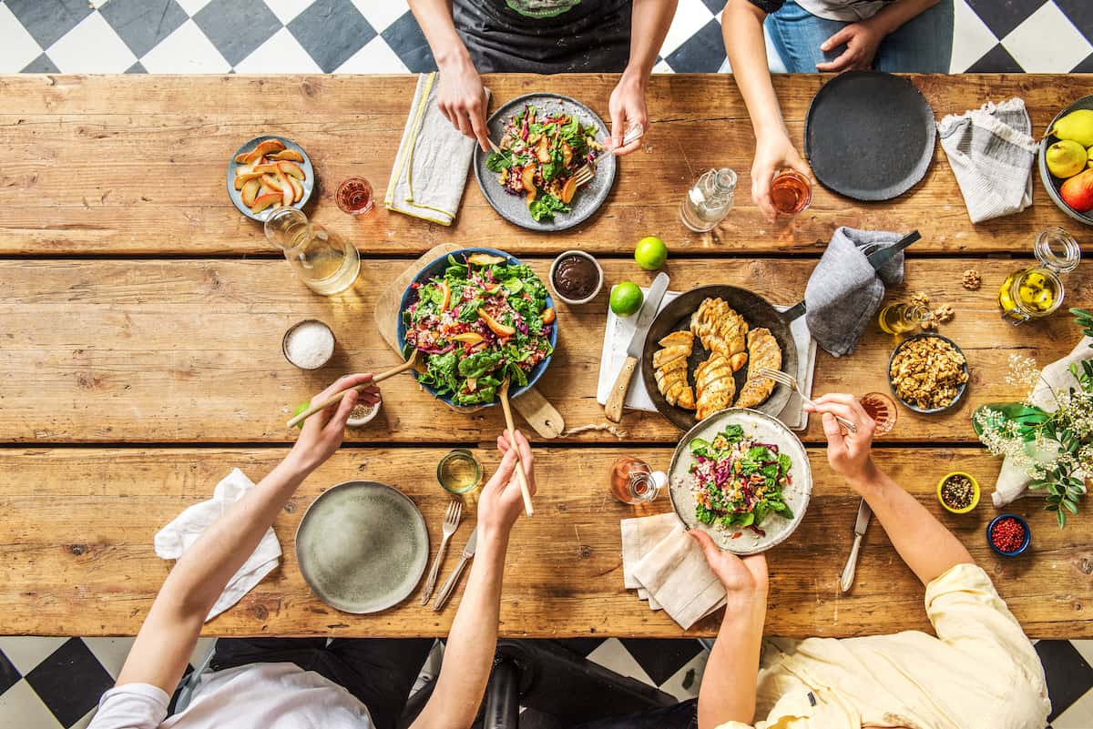 Genuss steht bei HelloFresh im Mittelpunkt: Ein gedeckter Holztisch mit Essen und mehreren Personen von oben fotografiert