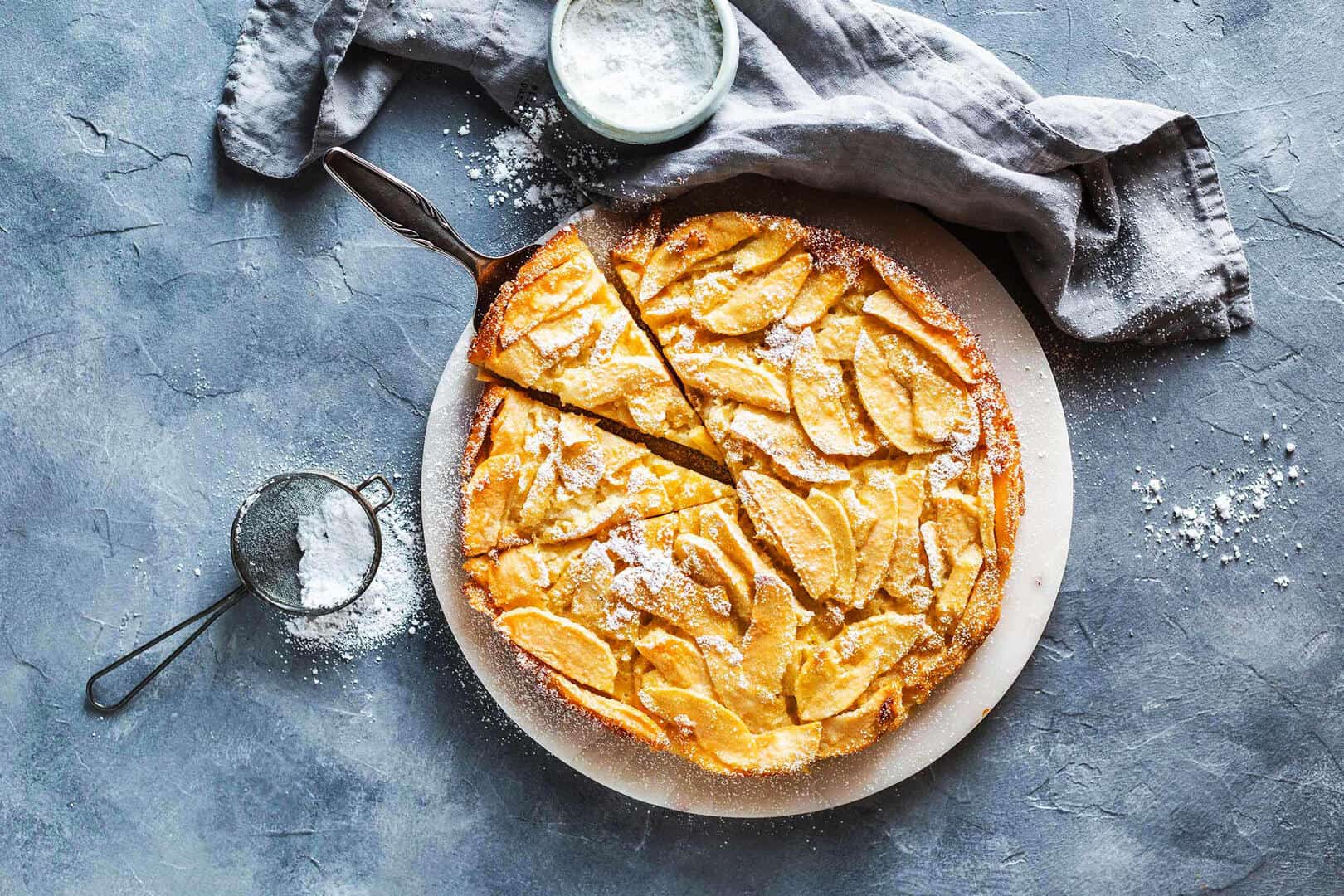 Toskanischer Apfelkuchen von oben fotografiert auf blau-grauem Untergrund– Foto: Anna Gieseler