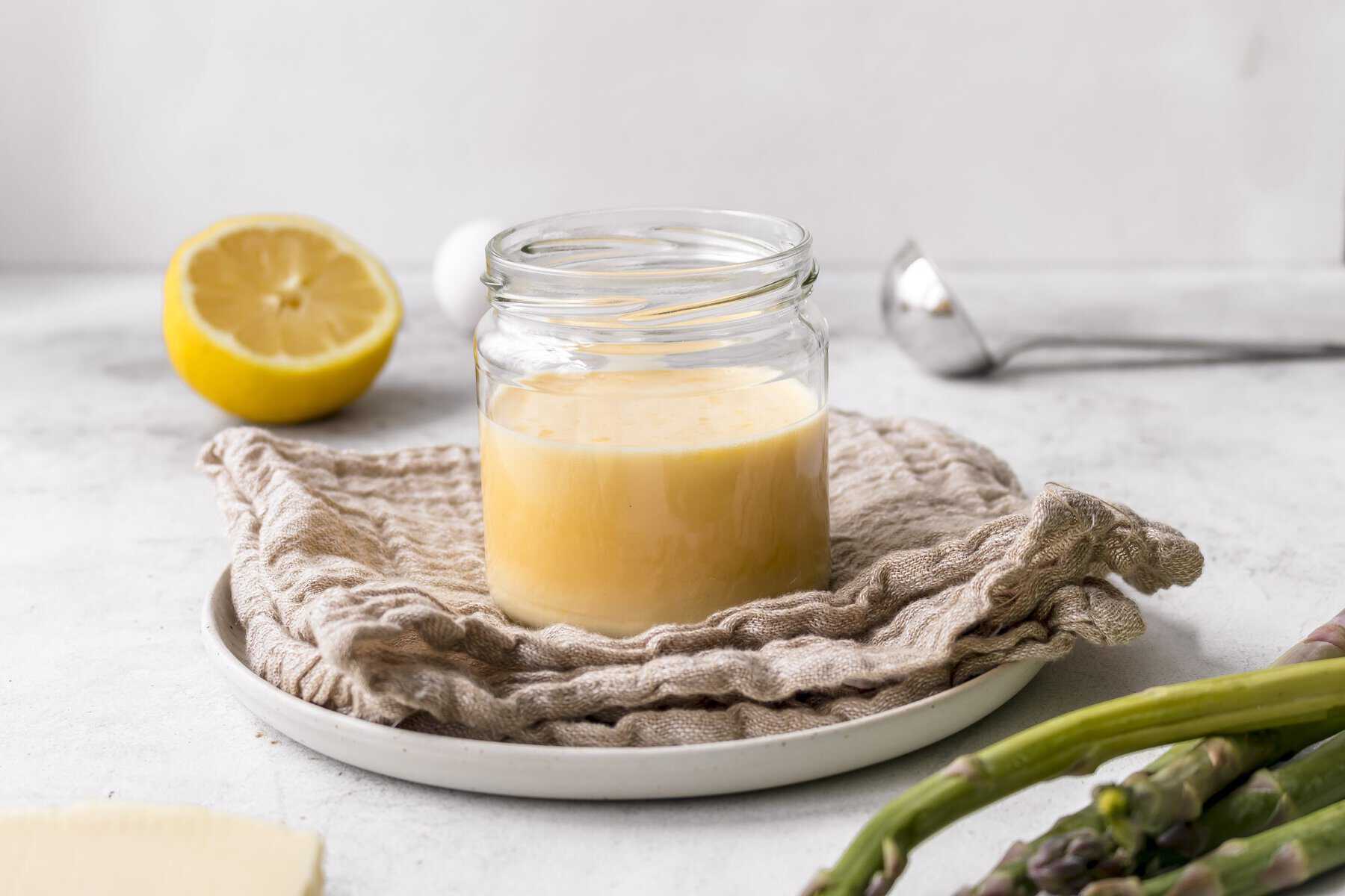 Sauce hollandaise in einem Glas, im Vordergrund grüner Spargel – Foto: Sandra Leibinger