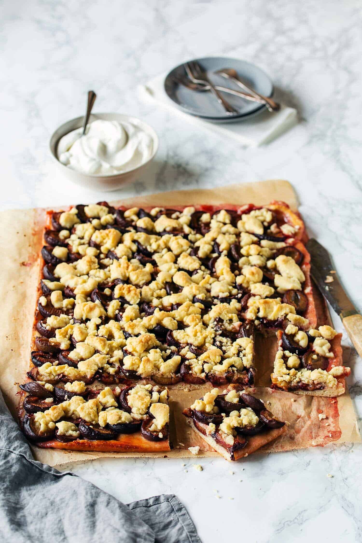 Pflaumenkuchen mit Quark-Öl-Teig auf hellem Untergrund, angeschnitten – Foto: Anna Gieseler