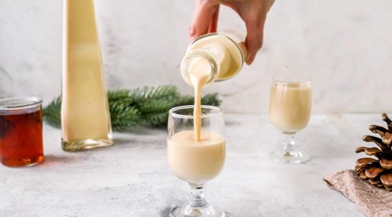 Jemand gießt cremigen, hellen Likör in ein Glas, daneben eine zweite Flasche Likör – Foto: Sandra Leibinger
